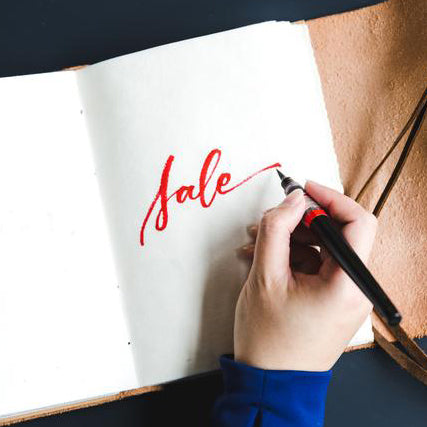 Handwritten word "sale" on a paper page in a notebook