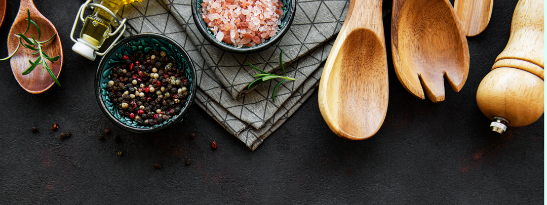 Lilybranch's Pantry Collection showcasing herbs, salts, wooden utensils, pepper mills and oils on a dark counter top