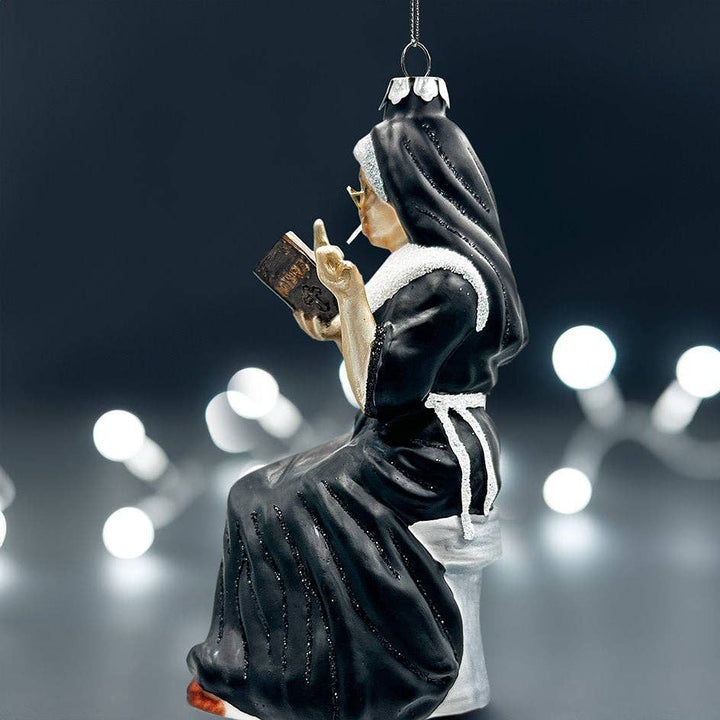Decorative ornament of a nun reading a book with blurred lights in the background
