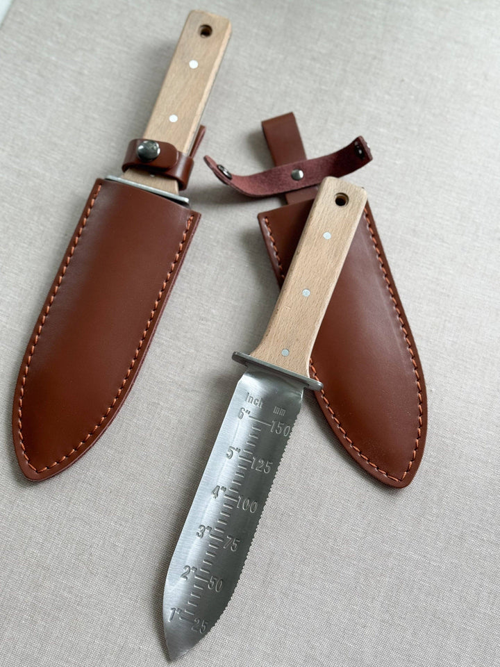 Two hunting knives with leather sheaths on a light gray background