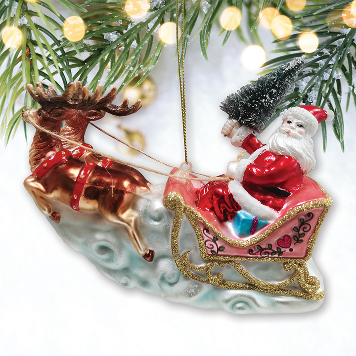 Decorative Christmas ornament of Santa Claus in a sleigh pulled by a reindeer, hanging from a tree.