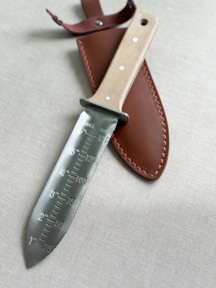 Knife with leather sheath on a light gray background