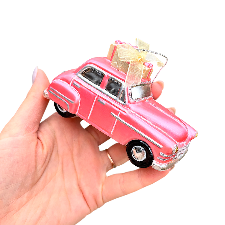 Pink vintage car model with a bow on a white background