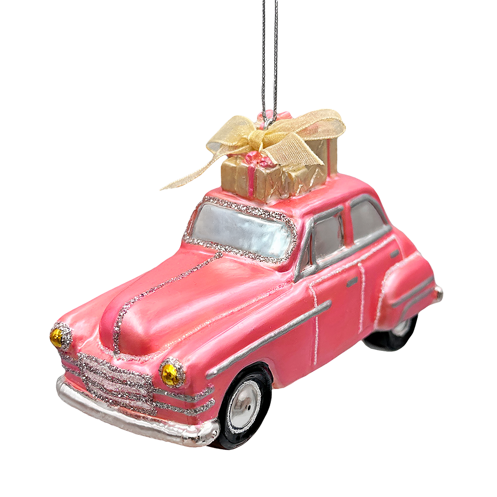 A pink vintage car Christmas ornament with silver trim, a gold gift box on its roof, and a hanging string, shown against a plain white background.