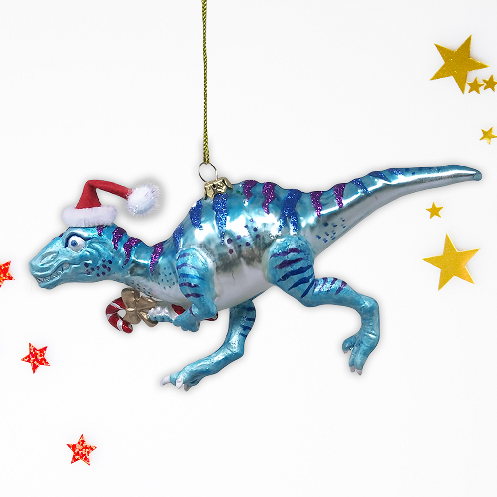 A blue and white dinosaur Christmas ornament with purple stripes, wearing a red Santa hat and holding a candy cane, shown on a white background with decorative star graphics.