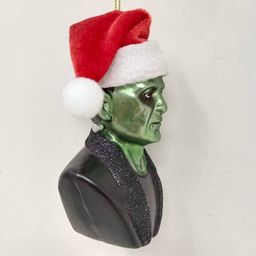 Green monster head ornament with a Santa hat on a white background