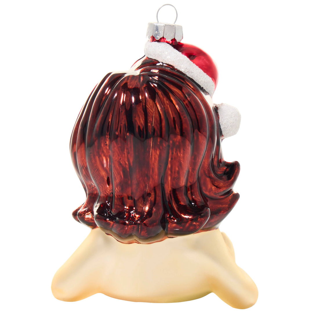 A Christmas ornament shaped like a woman's head with long, glossy dark red hair and a Santa hat, displayed on a cream-colored stand against a white background.