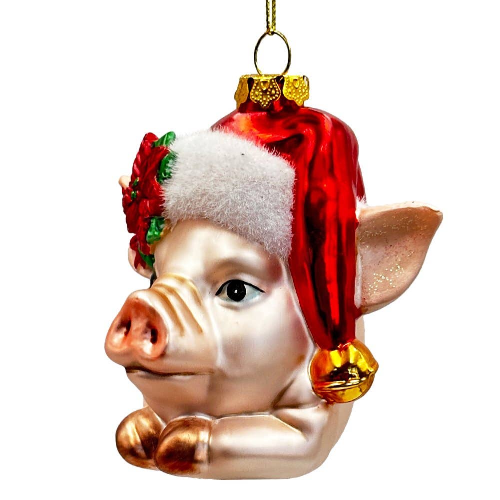 Glass pig ornament wearing a Santa hat with a white beard and red trim on a white background