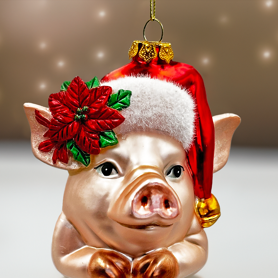 Pig-shaped Christmas ornament wearing a Santa hat and poinsettia flower on a neutral background