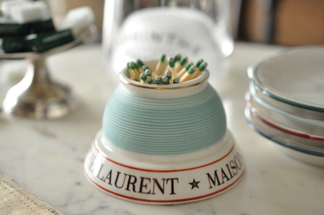 Match striker with matches on a marble surface, featuring 'Laurent Maison' branding.