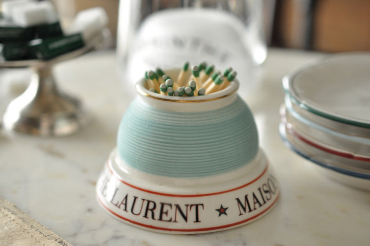 Match striker with matches on a marble surface, featuring 'Laurent Maison' branding.