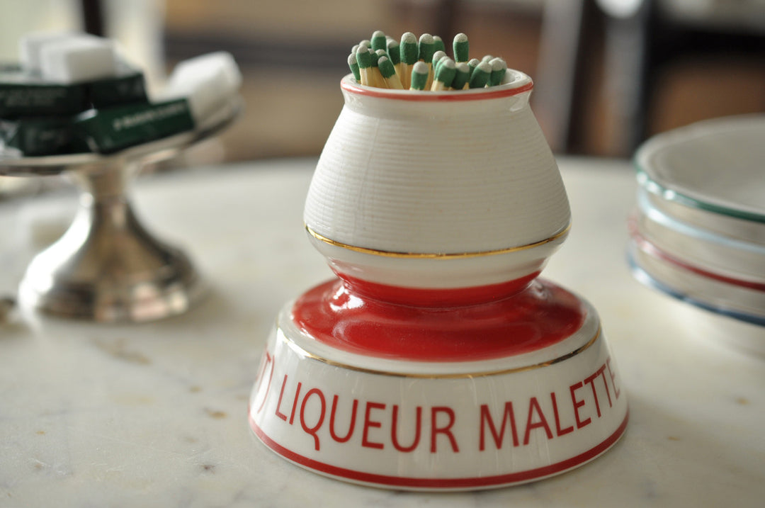 Decorative match striker with 'Liqueur Malette' text on a marble surface
