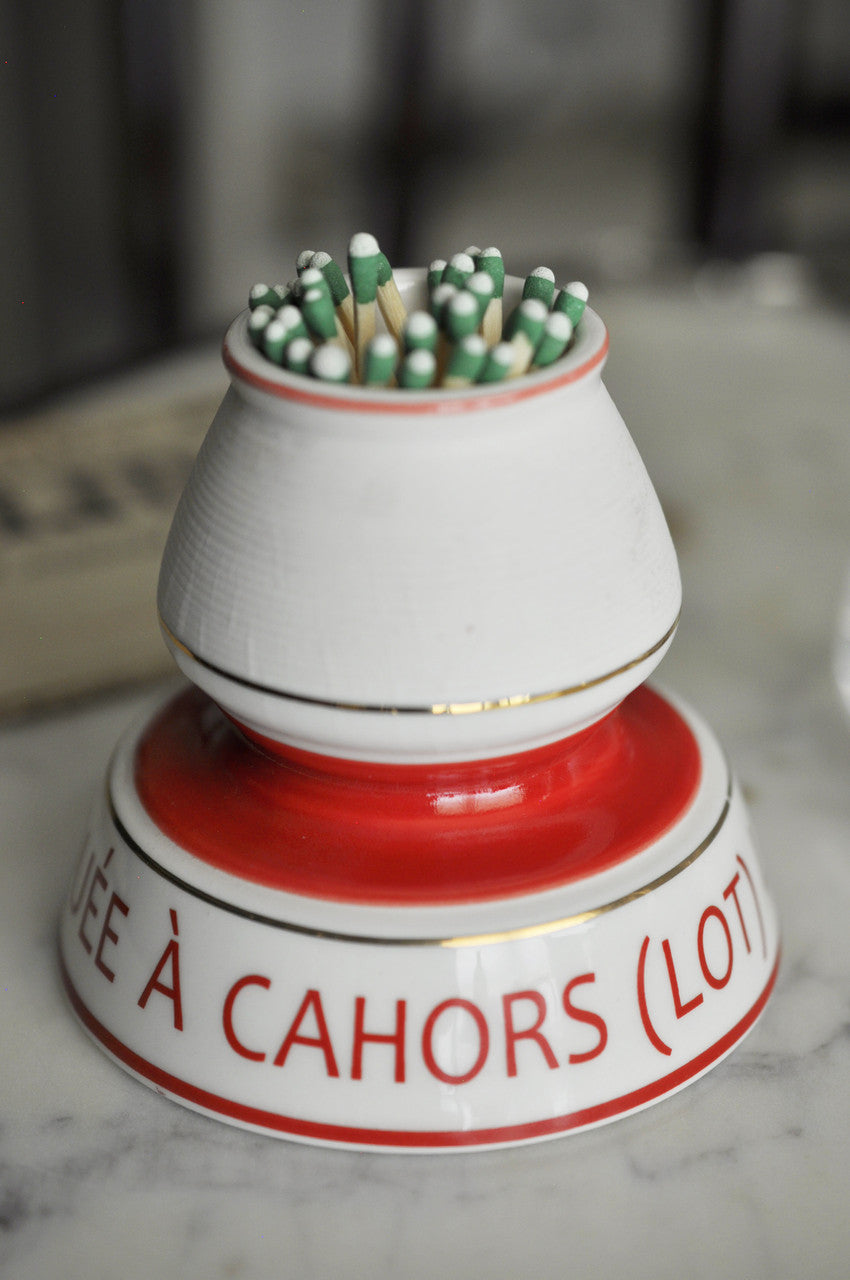 White and red ceramic match holder with matches on a marble surface