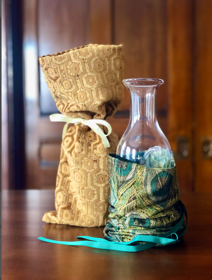 Glass ice carafe with fabric gift bag in gold pattern and a peacock feathers