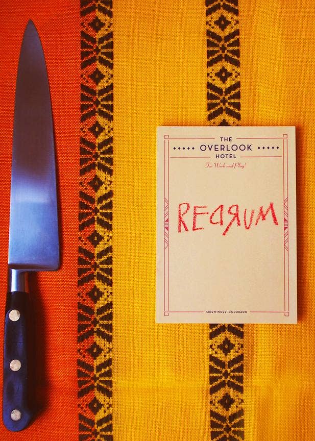 Knife and notepad with the text 'Redrum' on a patterned orange surface