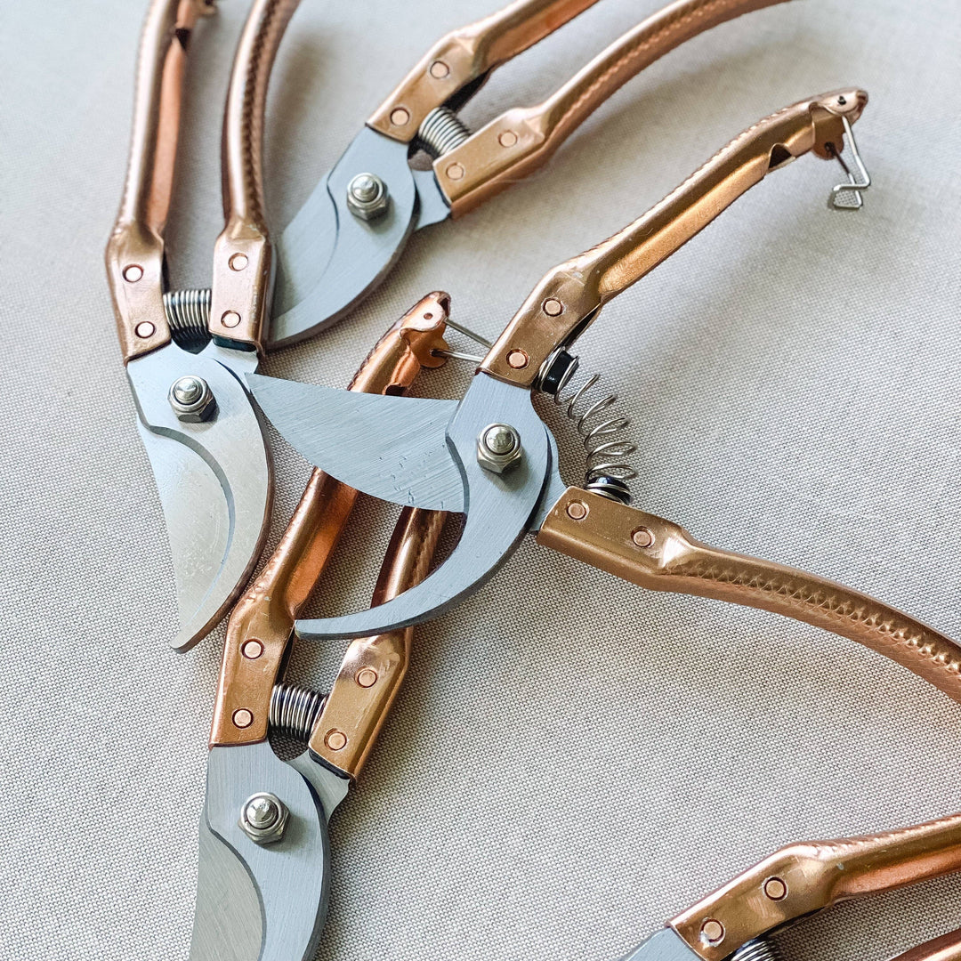 Pair of garden shears with copper handles on a light fabric background