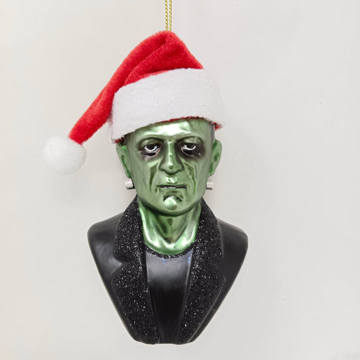 Ornament resembling a green horror creature with a Santa hat on a white background