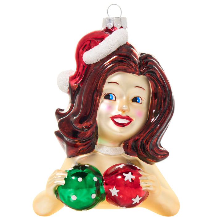 A vintage-style Christmas glass ornament depicting a smiling woman with red hair wearing a Santa hat and holding red and green ornaments.